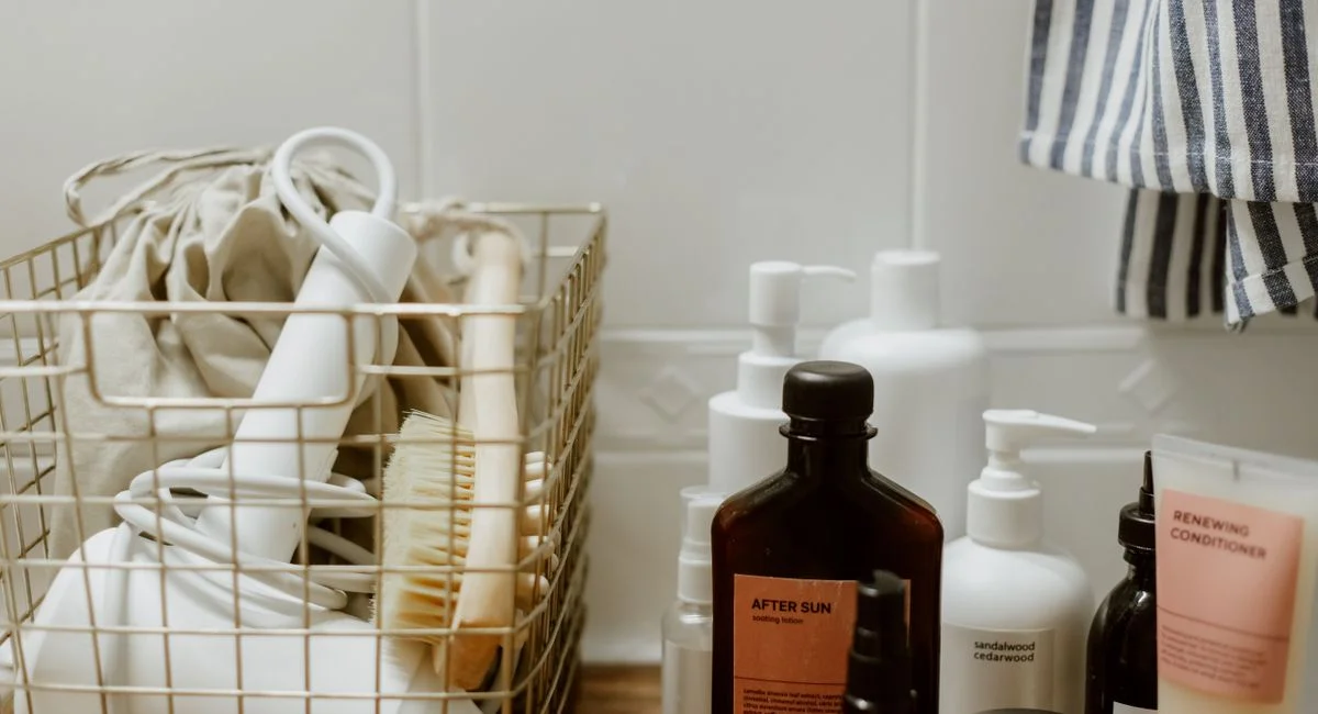 Aesthetic arrangement of bathroom products and accessories in a wire basket on a wooden shelf.