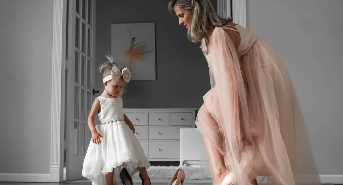 A woman and a child in elegant dresses enjoying a fashion moment indoors.